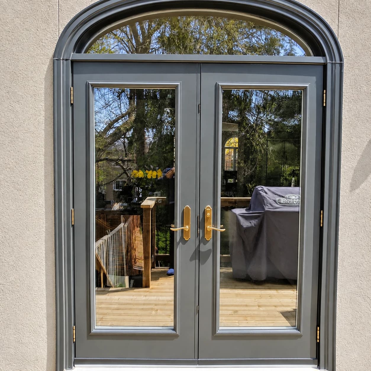 Glass double doors with an arched transom and grey frames