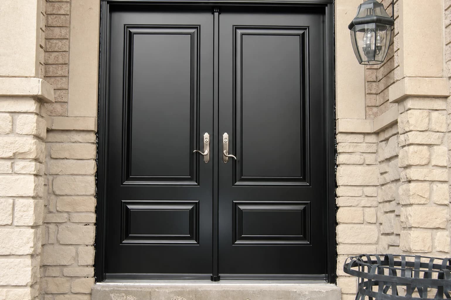 Black double entry doors with brass hardware in a stone surround