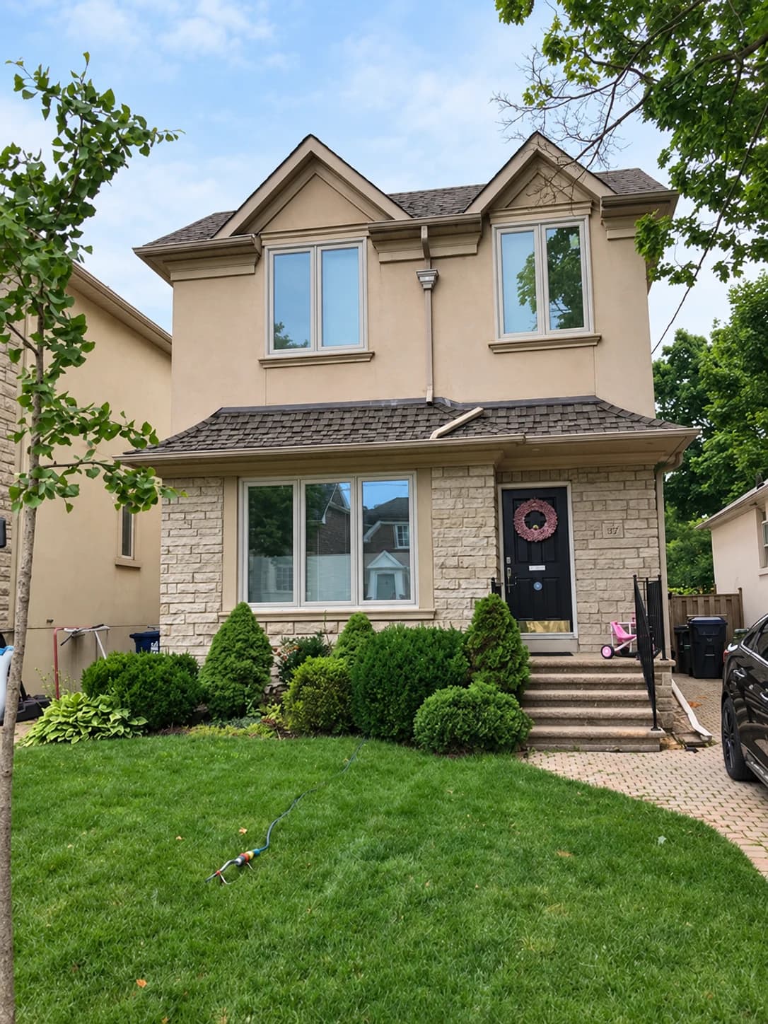 Stone and stucco home with white windows and a black front door