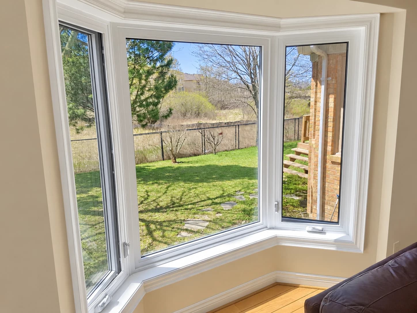 White bay window with an open side panel overlooking a backyard