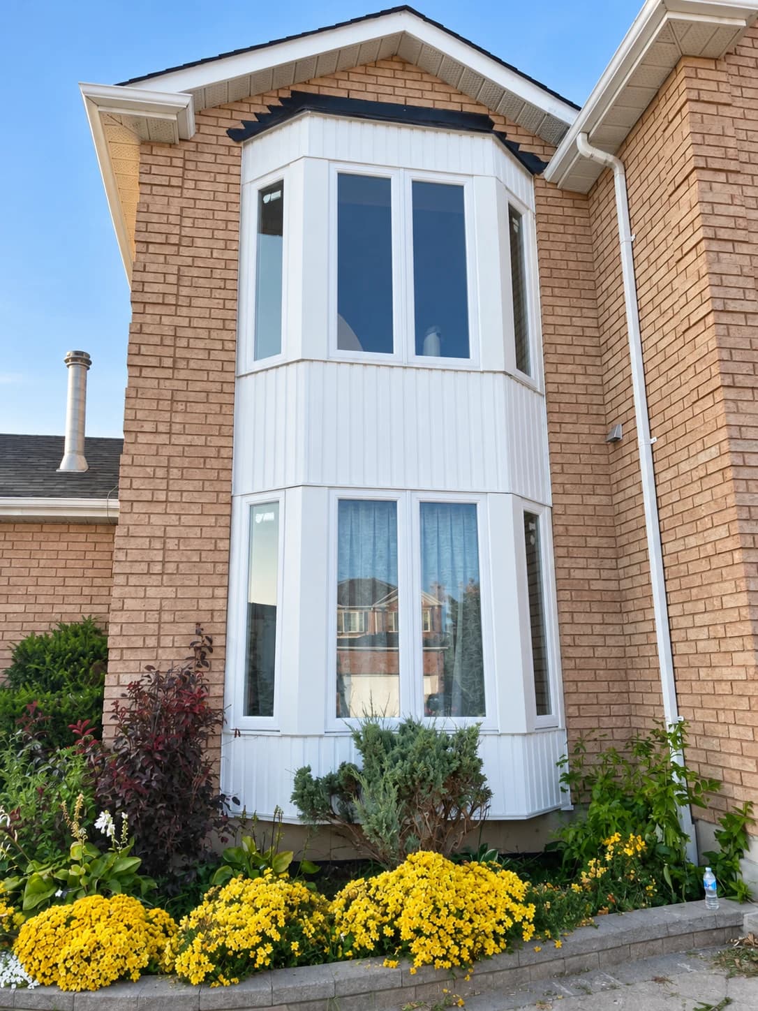 White bay windows on two storeys of a brick home